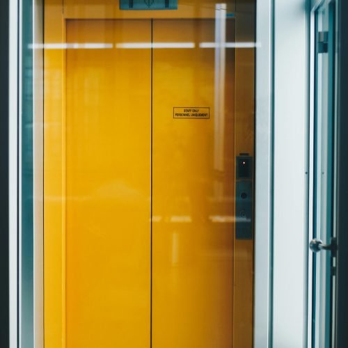 A bold yellow elevator door captured indoors, offering a bright contrast in modern architecture.